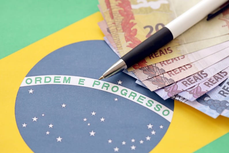 Pen and cash on top of Brazilian flag