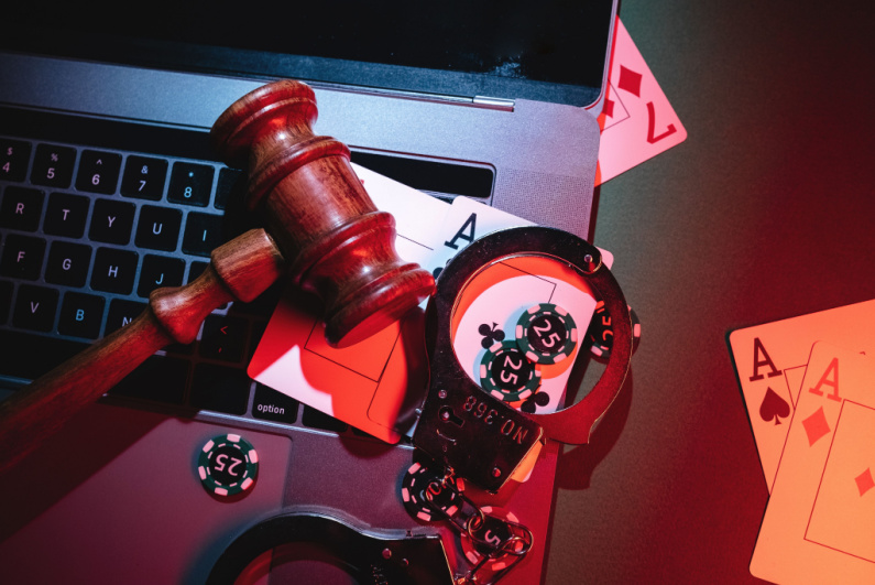 Gavel, playing cards, and handcuffs on a laptop