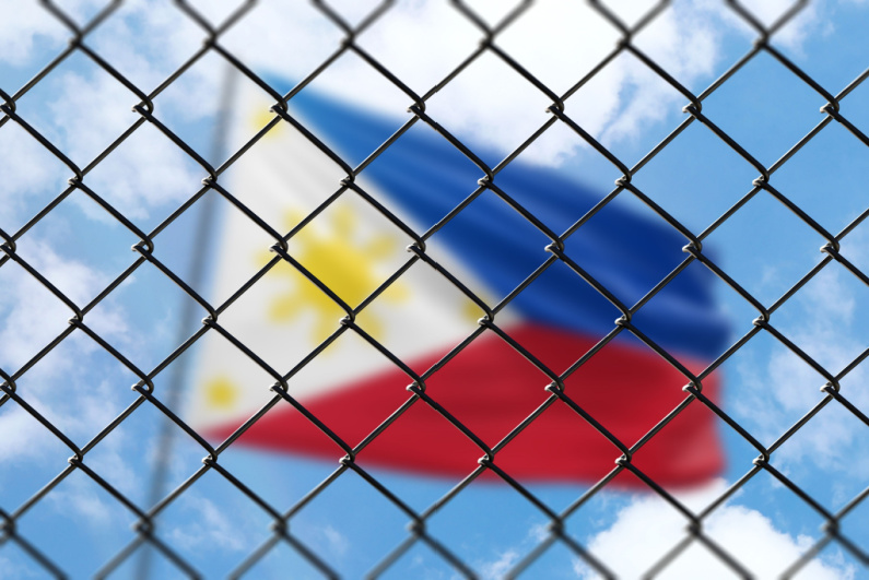 Blurred Philippines flag behind chainlink fence