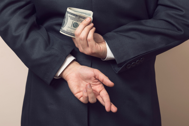 Businessman holding money behind his back with his fingers crossed