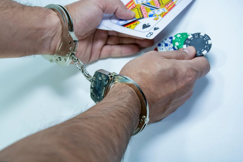 Handcuffed man holding cards and chips