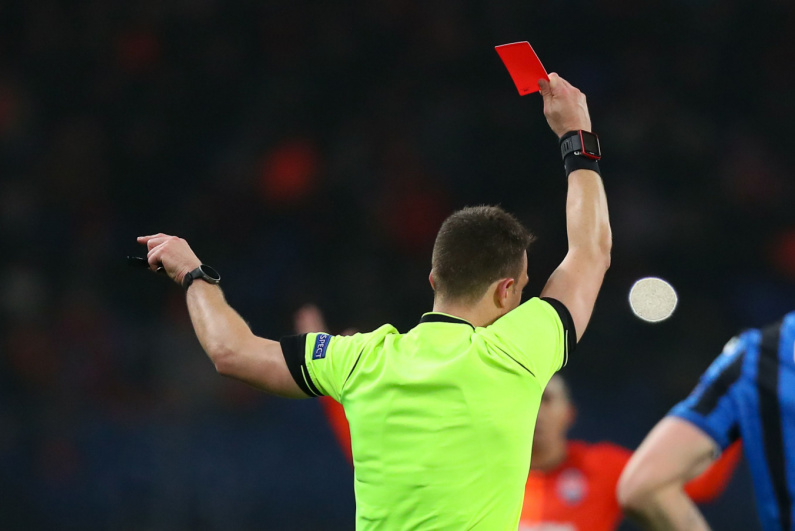 A football referee issues a red card