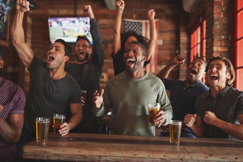 Men cheering while watching a football game at a sports bar