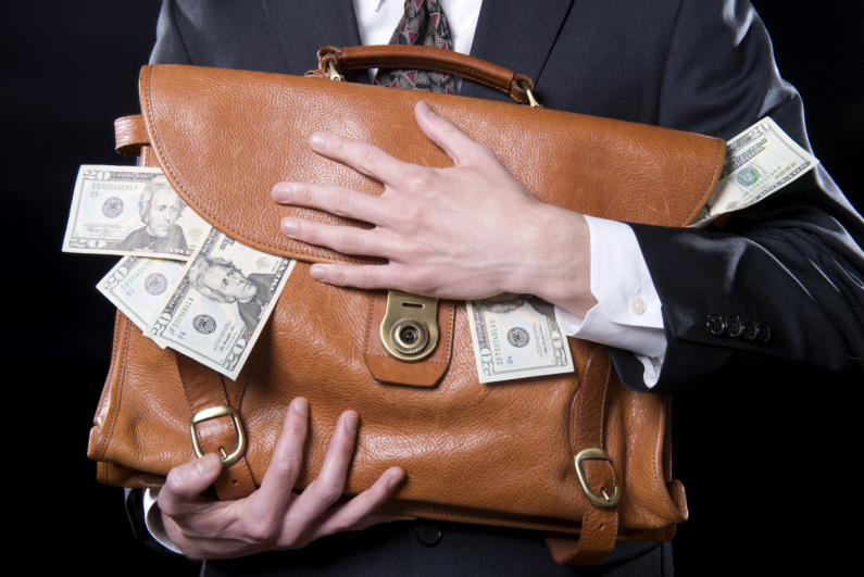 Man clutching briefcase overflowing with cash