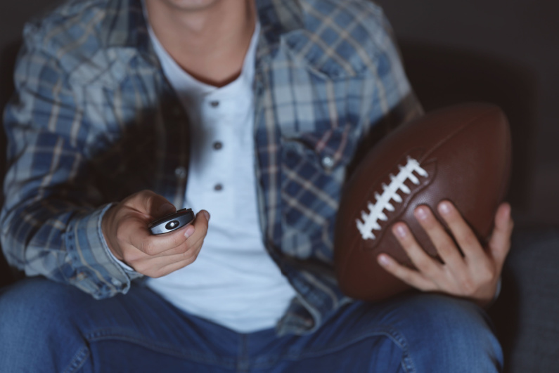 Closeup of sports fan holding remote control