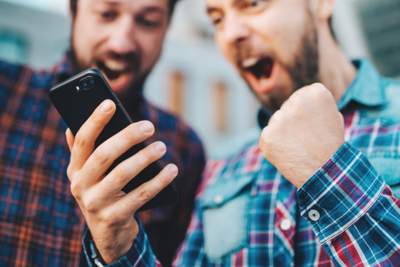 Men cheering about something on their phone