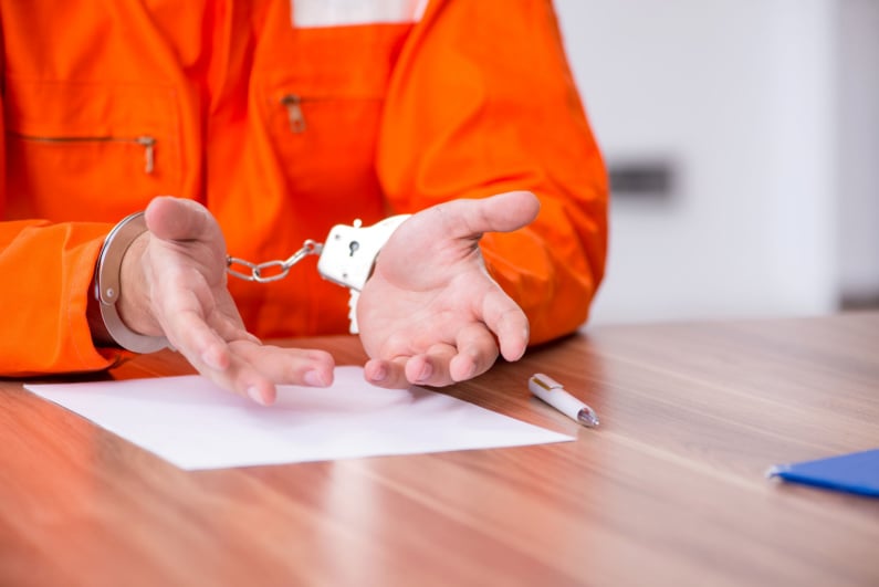Closeup of man's shackled hands at a parole hearing