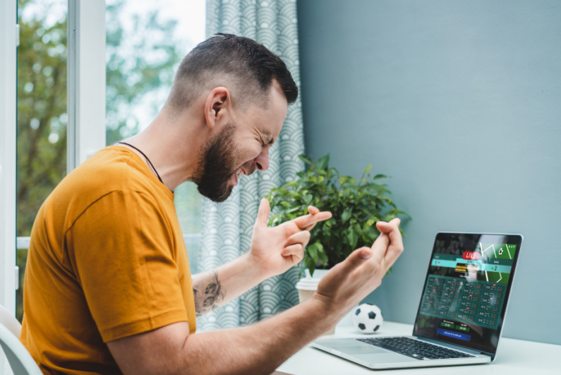 Man crossing his fingers watching sports scores