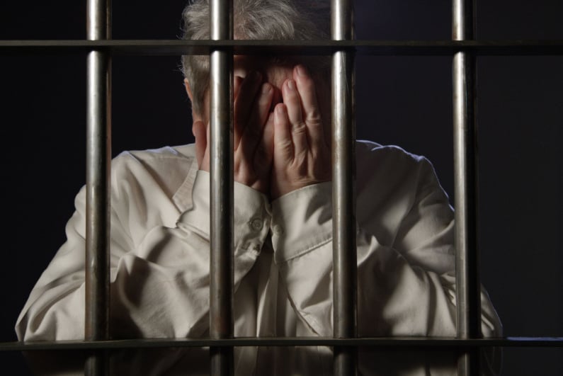 An elderly woman behind bars