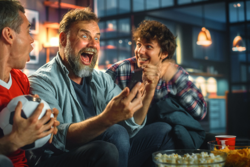 Sports fan celebrating while looking at his phone