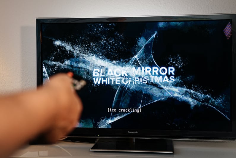 Person turning on Black Mirror with a remote control