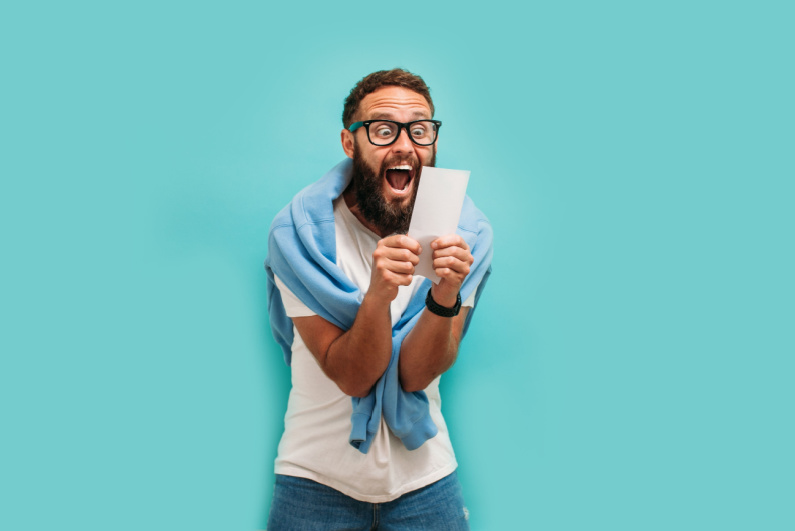 Man cheering holding winning lottery ticket