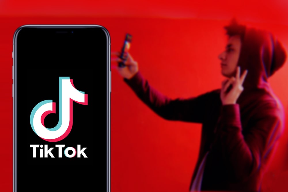 TikTok logo and man filming himself
