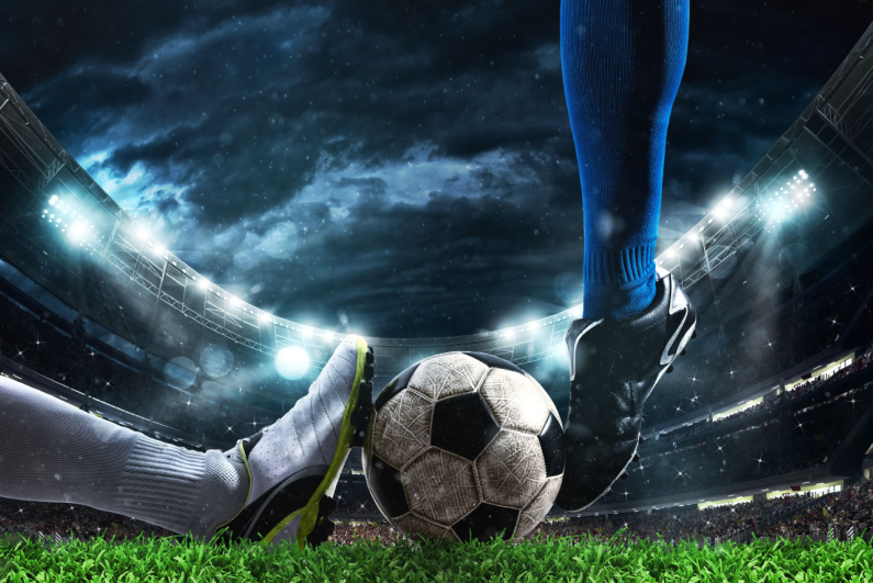 Close up of soccer players' feet striking ball