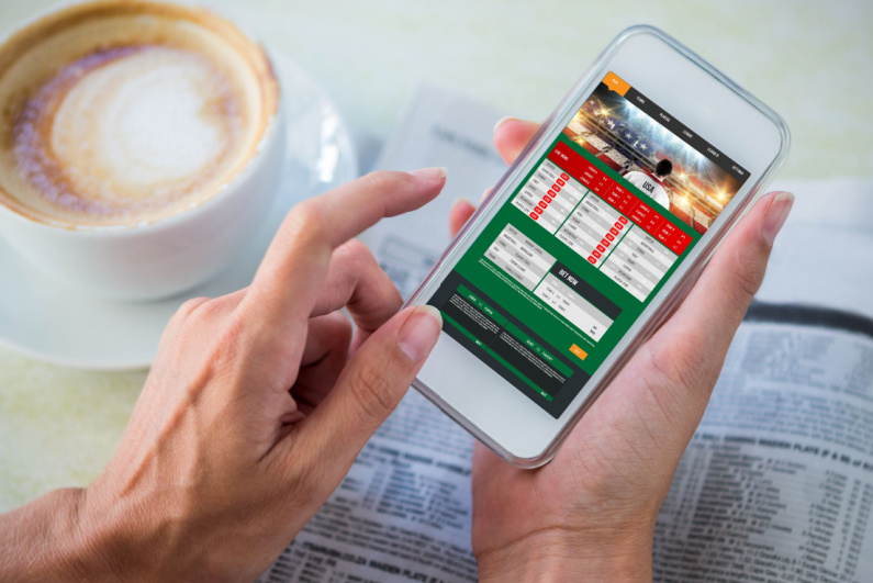 Person using a sports betting app over a cup of coffee