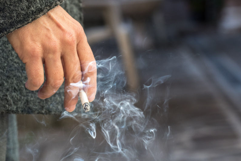Hand holds burning cigarette