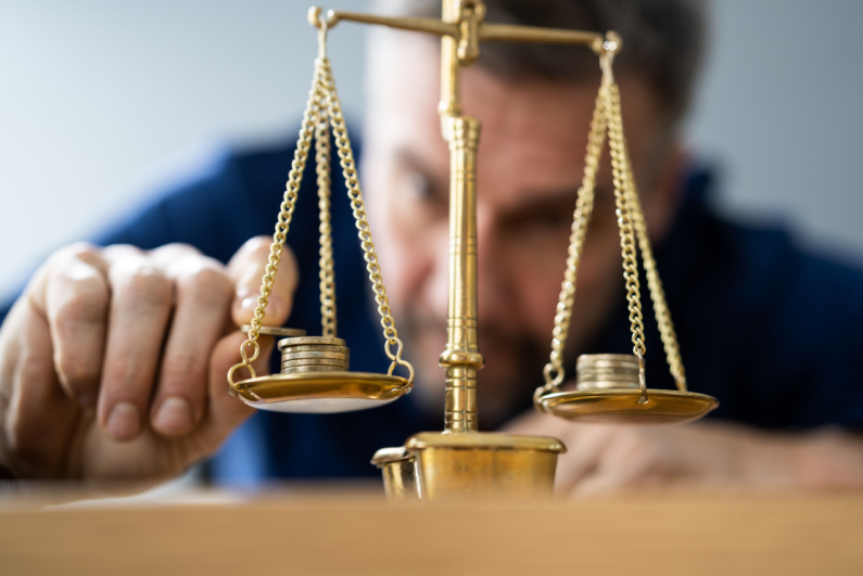 A man balances coins on a scale