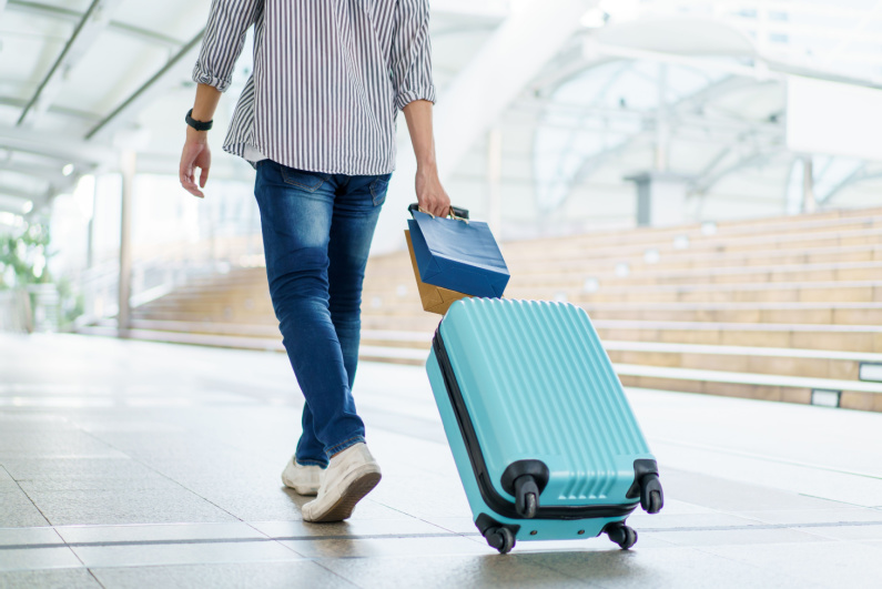 A man walks through the airport with a suitcase