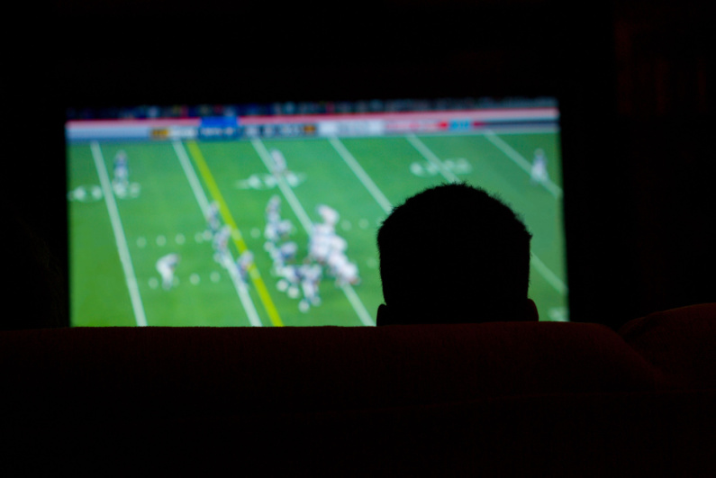 Silhouette of man watching a football game