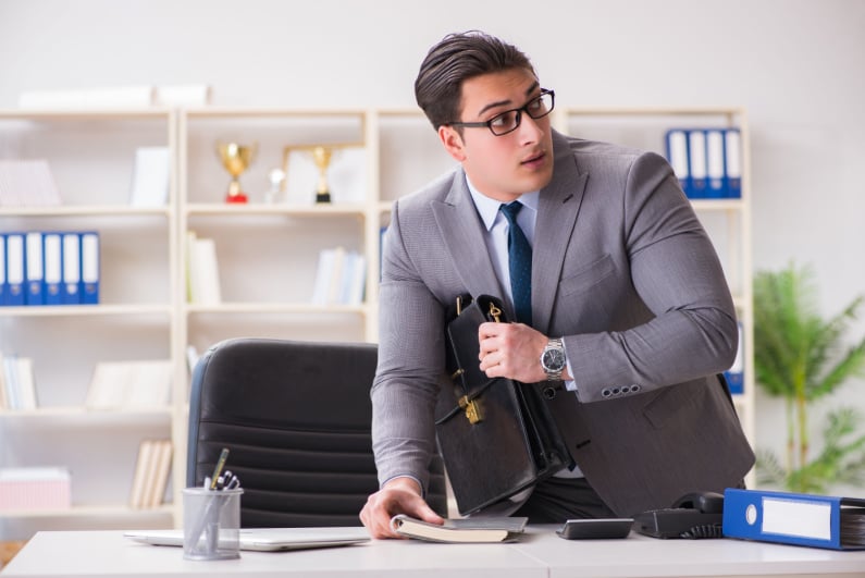 Businessman stealing notebook off desk