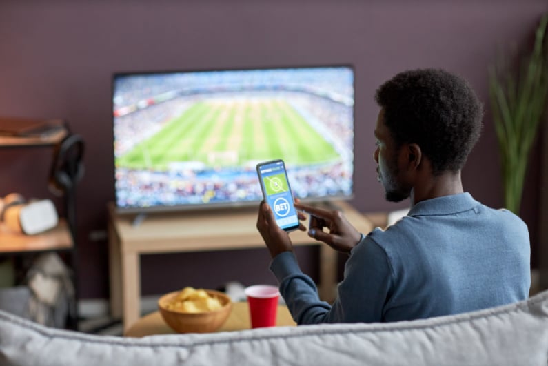 Man placing sports bet on his phone