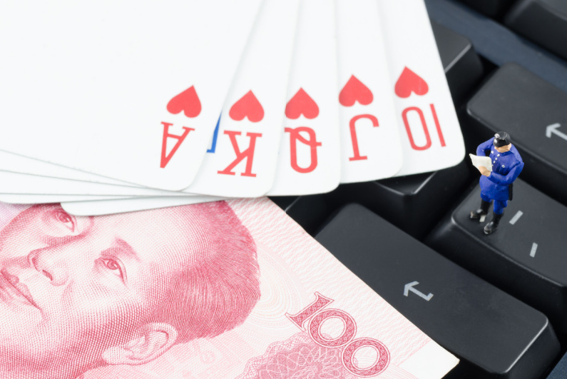 Miniature policeman at keyboard with cards and Chinese coin