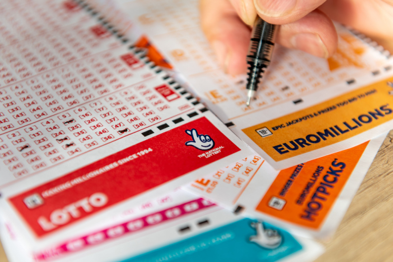 Person filling out UK National Lottery tickets