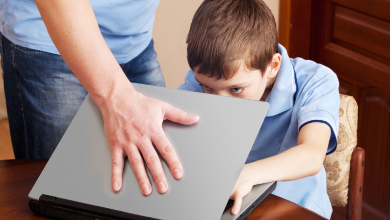 Boy trying to use laptop while dad closes it