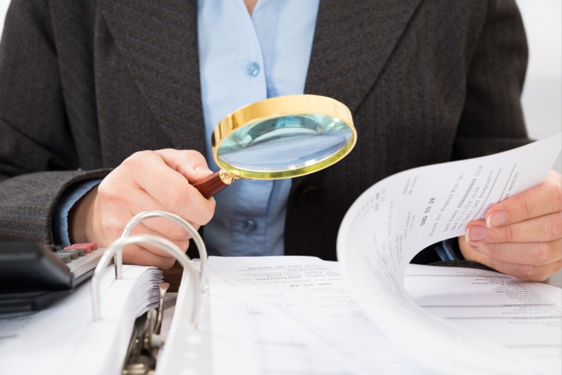 Man looking at papers with magnifying glass