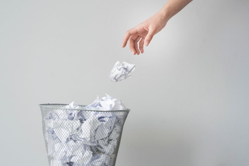 Person throws paper in the trash