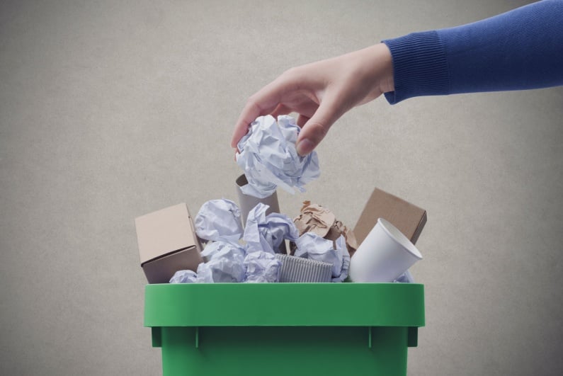 Person putting crumpled paper in the garbage