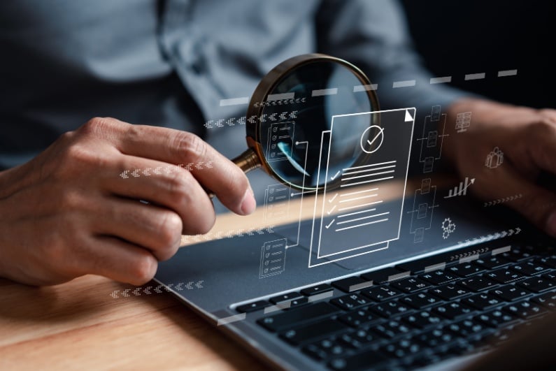 Person reading laptop image with magnifying glass