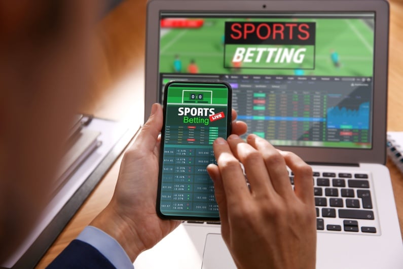 Person sports betting on phone and laptop