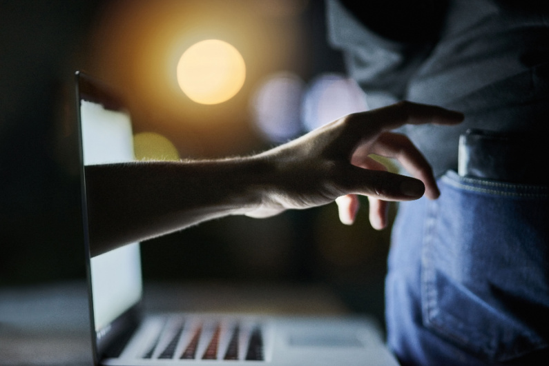 Hand reaching out of computer to take wallet