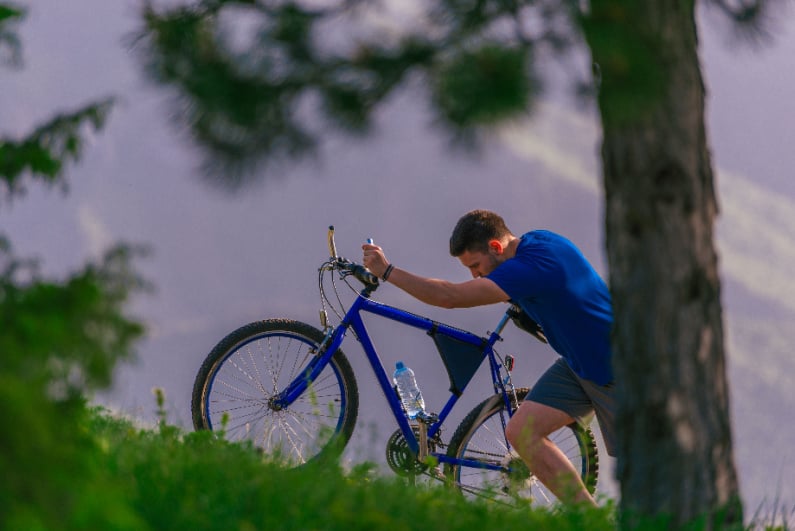 Tired cyclist pushing bike up hill