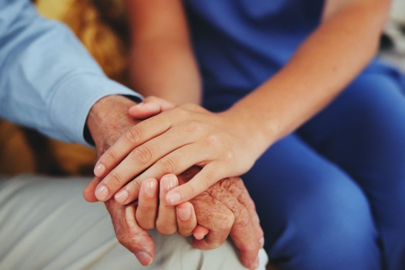 Nurse holding hand of elderly person