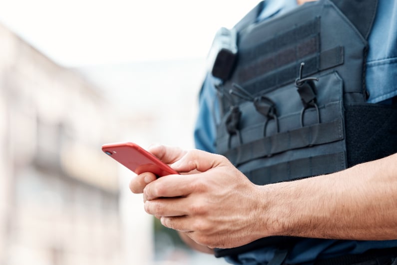 Police officer typing on phone