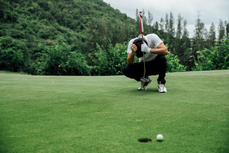 Golfer looking sad next to hole
