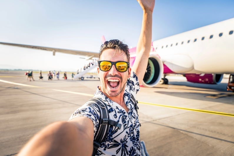 Happy man posing for selfie outside plane