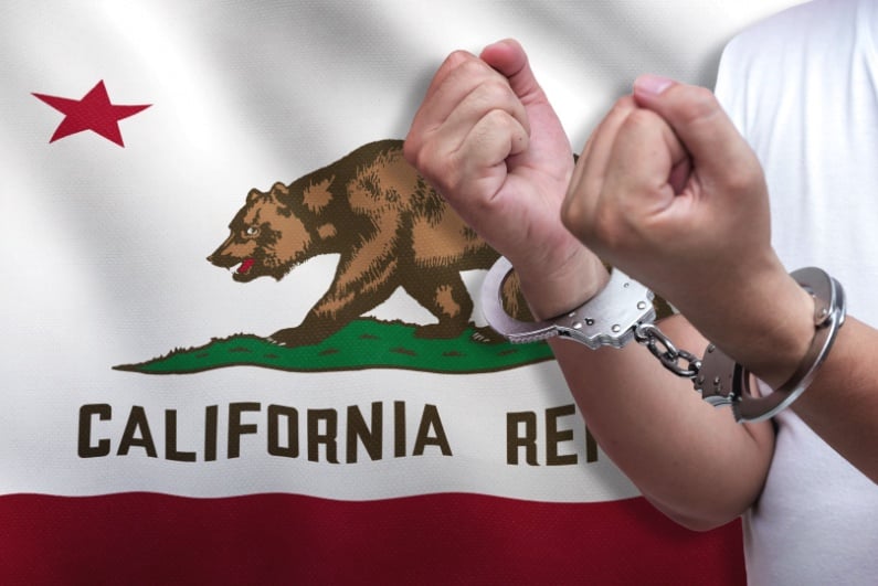Man in handcuffs in front of California flag
