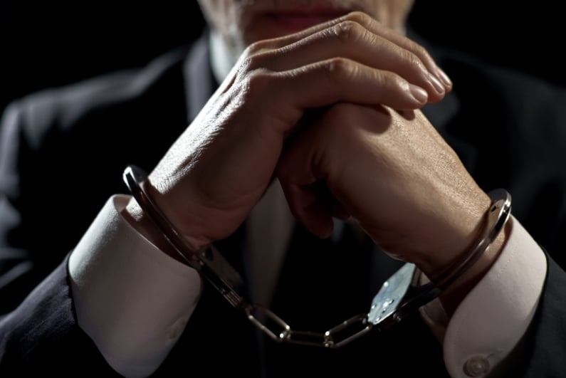 Man in suit wearing handcuffs