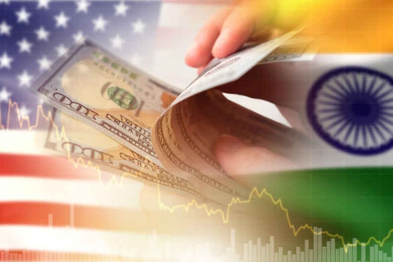 Person holding cash with US and India flags in background