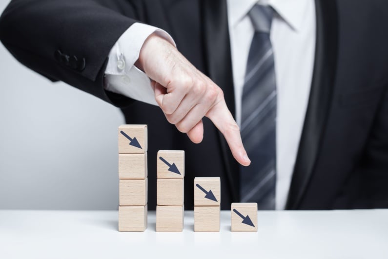 Businessman pointing down declining stacks of blocks