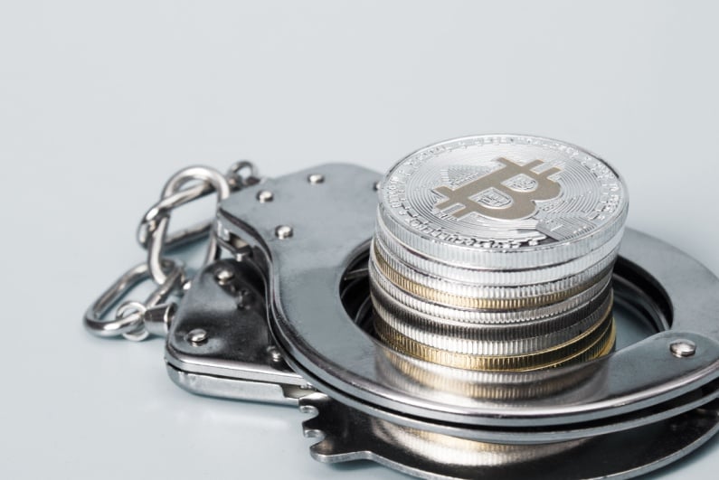 Handcuffs and stack of physical Bitcoin