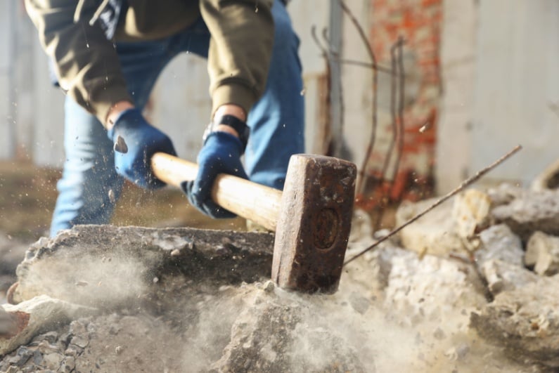 Man breaking stones with sledgehammer