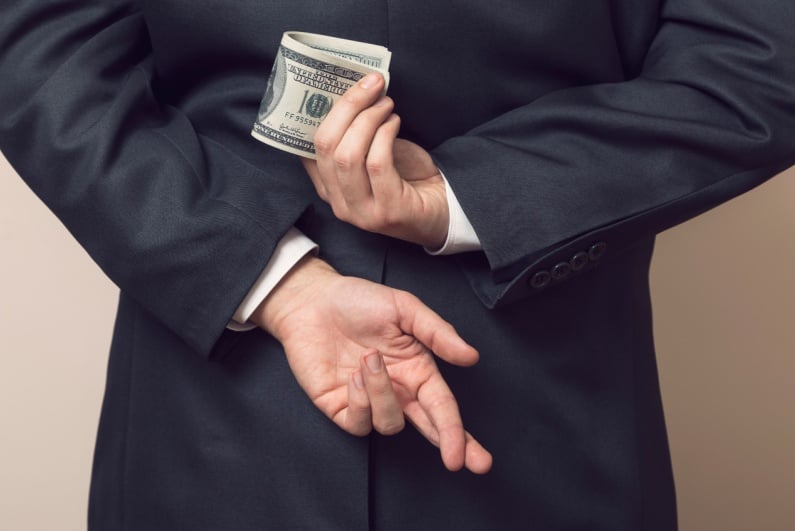 Man holding cash and crossing fingers behind back