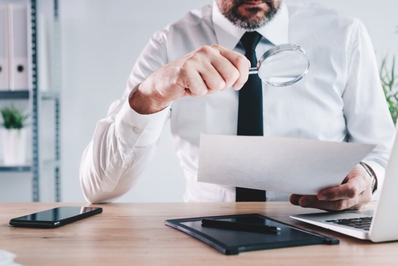Man reading paper with magnifying glass