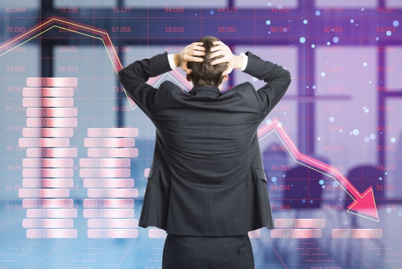 Man with head in hands seeing stock price down