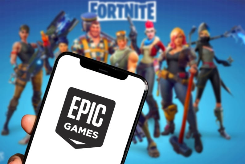 Epic Games logo on phone with Fortnite in background