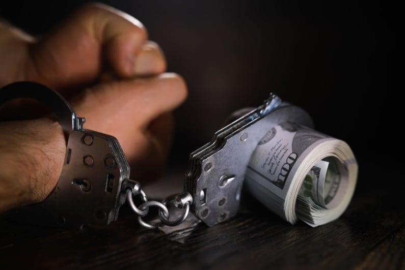 Handcuffs around wrist and cash